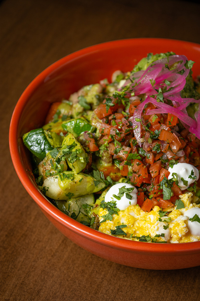 Breakfast bowl with scrambled eggs, roasted vegetables, pico de gallo, pickled red onions.