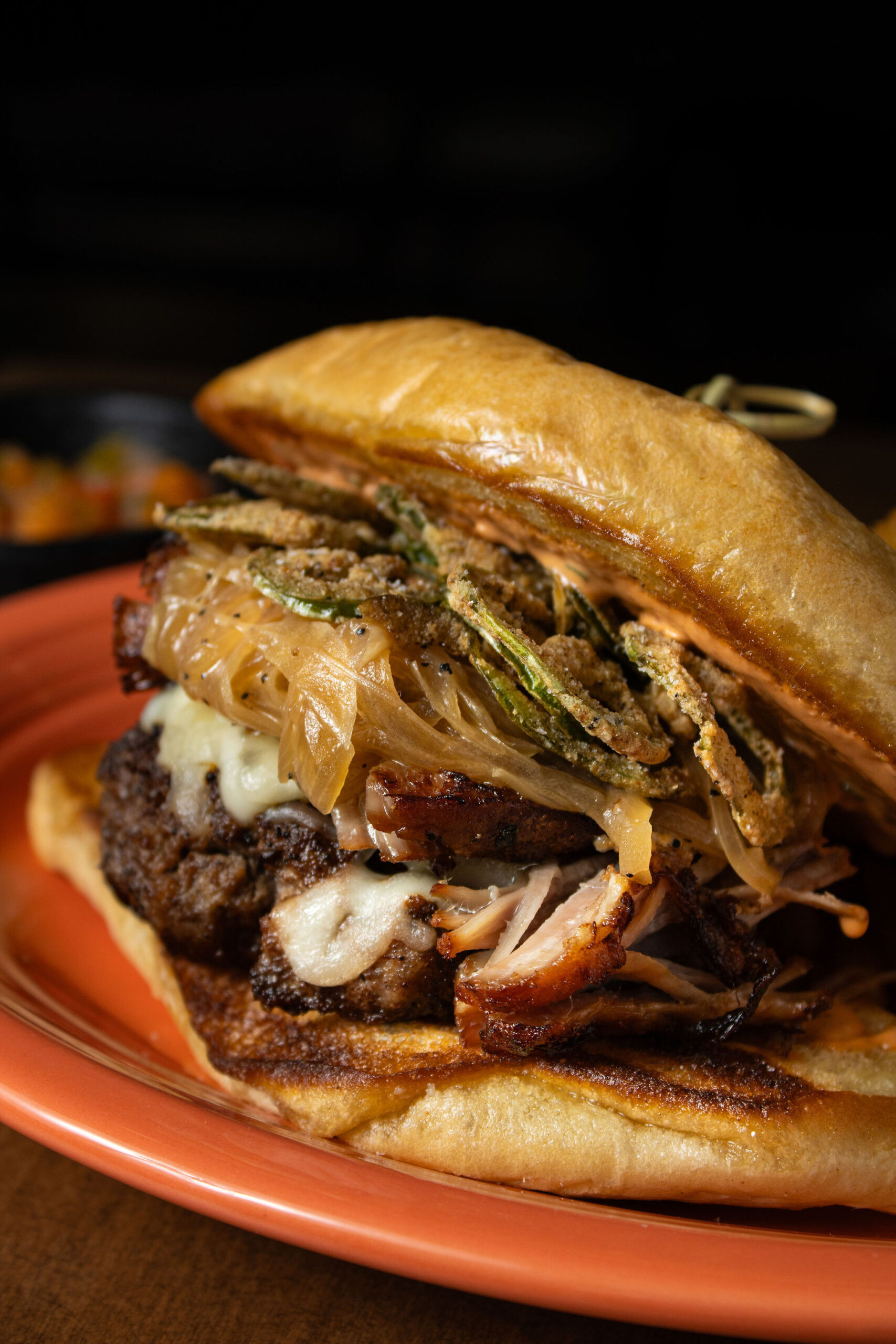Loaded burger topped with melted cheese, smoked meat, caramelized onions, and crispy fried jalapeños.