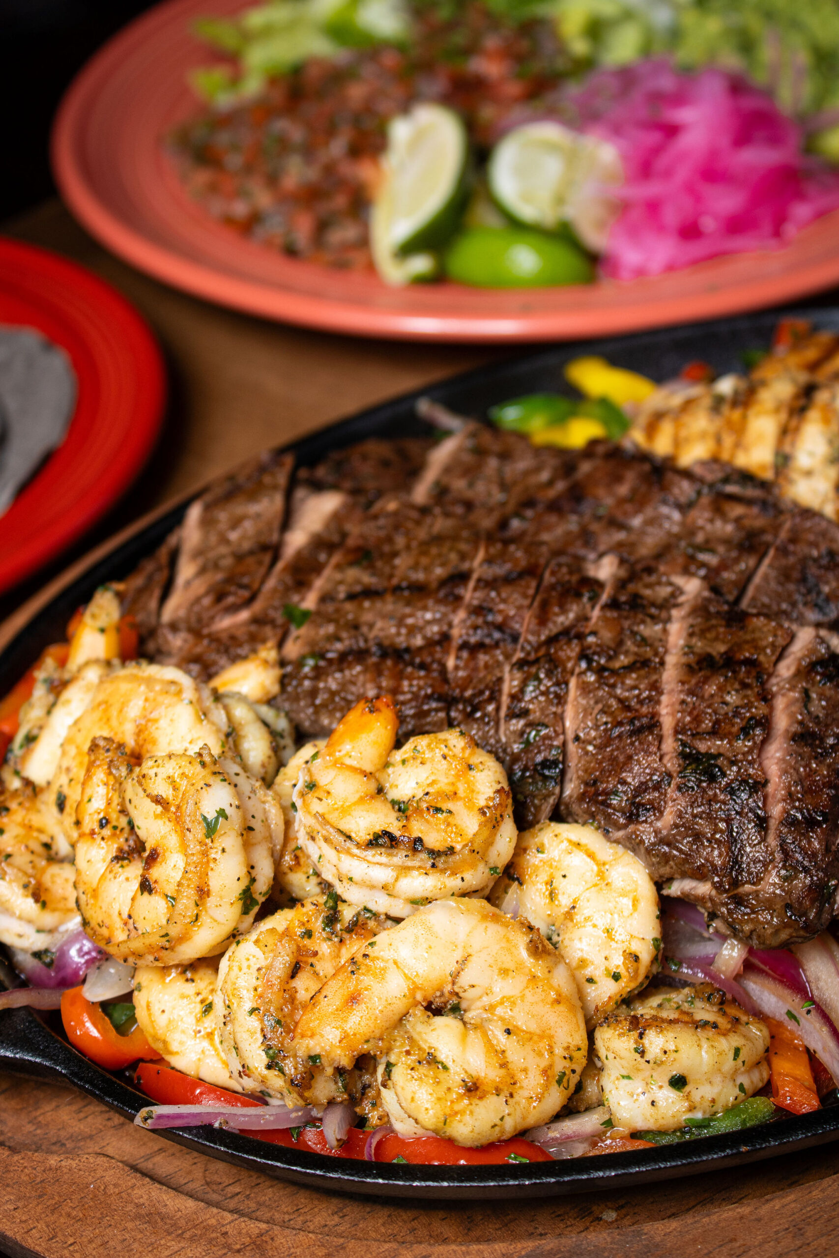 Grilled steak and shrimp fajitas served with peppers, onions, lime, and fresh toppings.
